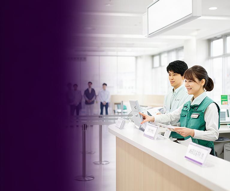 明るい市役所の総合窓口で番号案内を確認する来庁者と職員